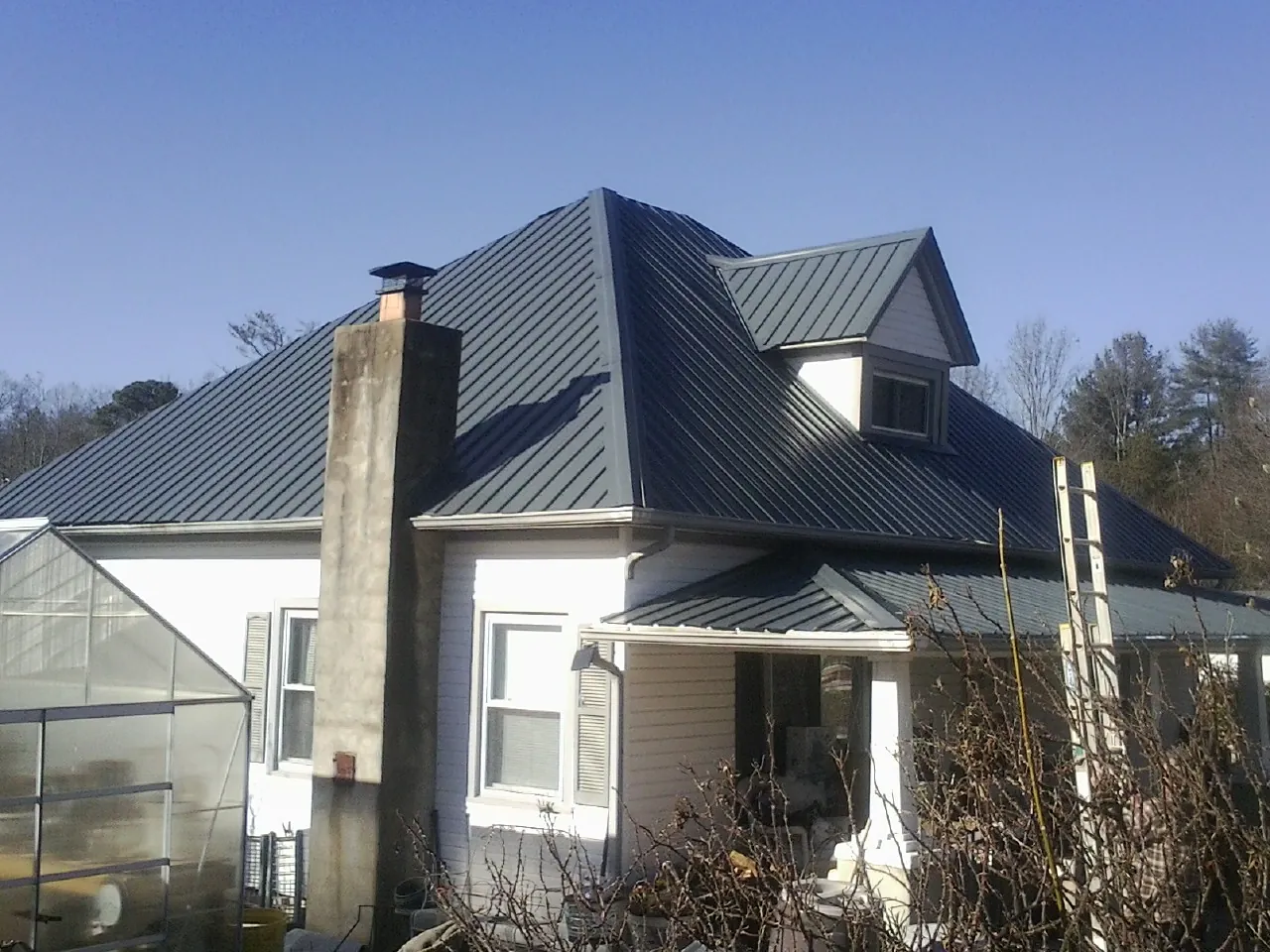 Dark blue standing seam metal roof on a white farmhouse with dormer — Slate & Tile Roof Repair by Roofing Brothers in Abington