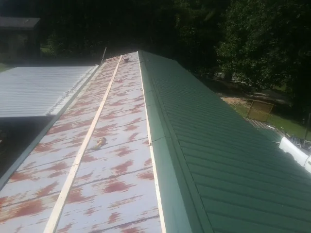 Old rusted panels beside newly installed green metal roofing — Wind Damage Roof Repair by Roofing Brothers in Abington