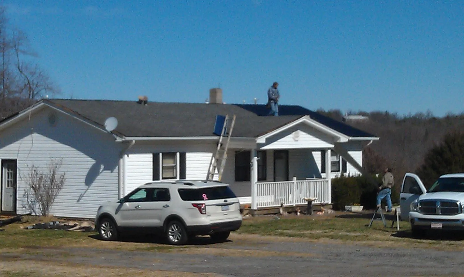 Roofers stripping shingles from a white ranch house roof in Abington